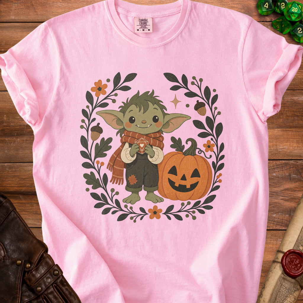 Pink t-shirt with cartoon creature, pumpkin, and floral wreath design.