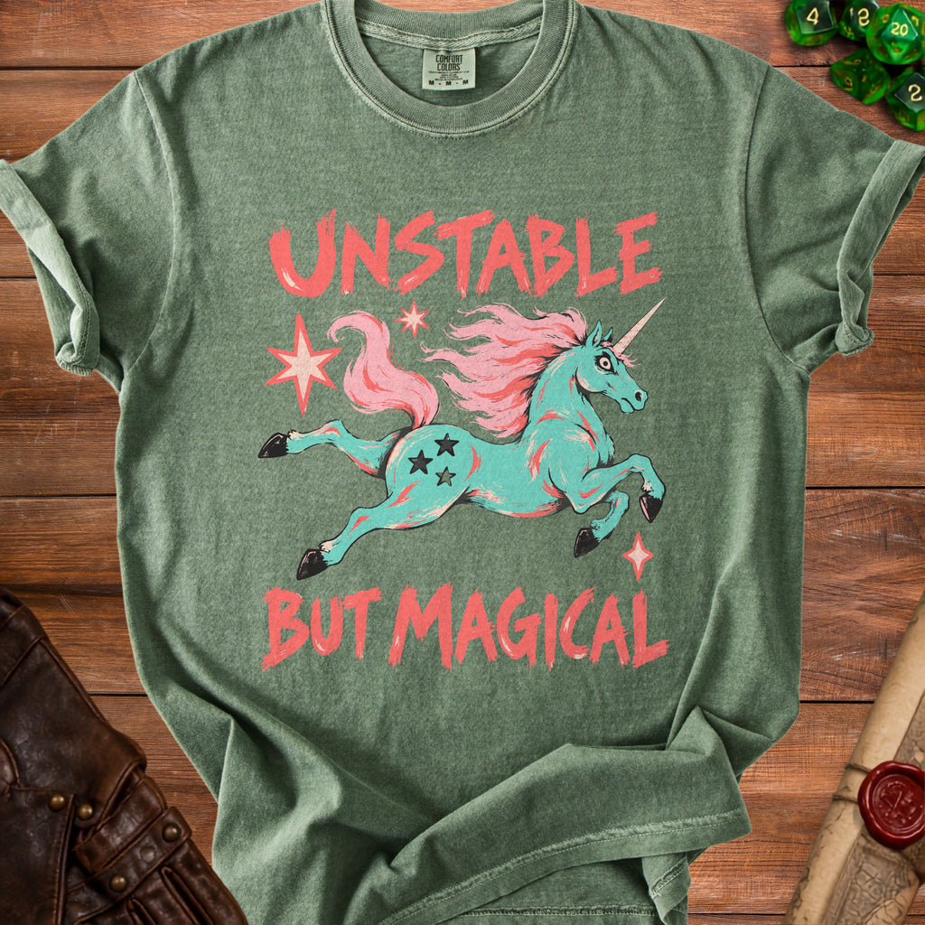 Green t-shirt with aqua unicorn graphic and coral text "UNSTABLE BUT MAGICAL".