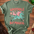 Green t-shirt with aqua unicorn graphic and coral text "UNSTABLE BUT MAGICAL".