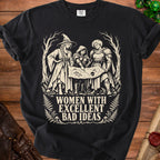 Black t-shirt with women examining a map, text reads "Women with excellent bad ideas."