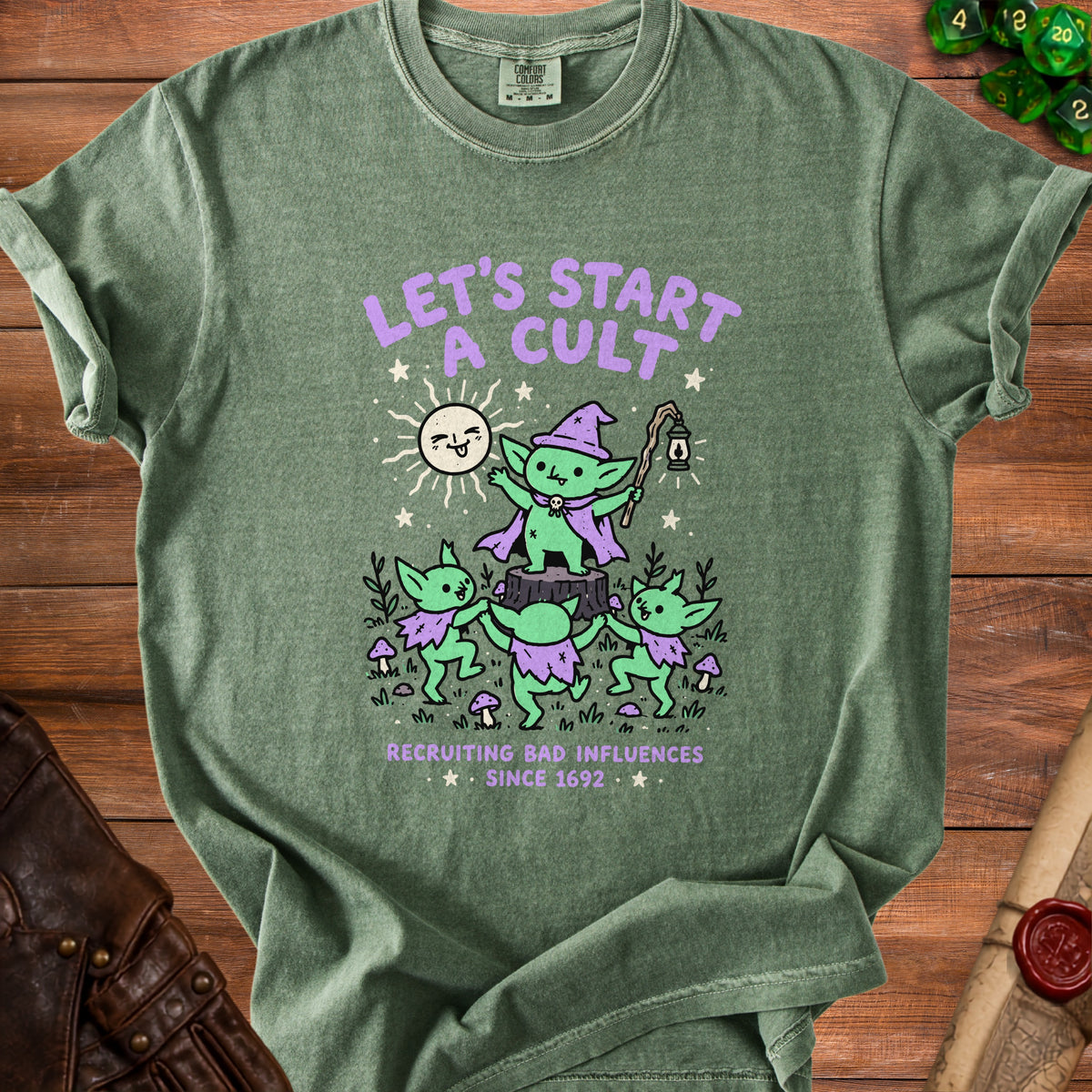 Green t-shirt with cartoon goblins and text "Let's Start A Cult Recruiting Bad Influences Since 1692".