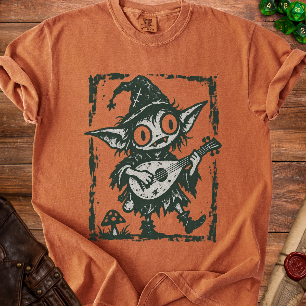 Goblin playing a lute on an orange shirt with a distressed print.