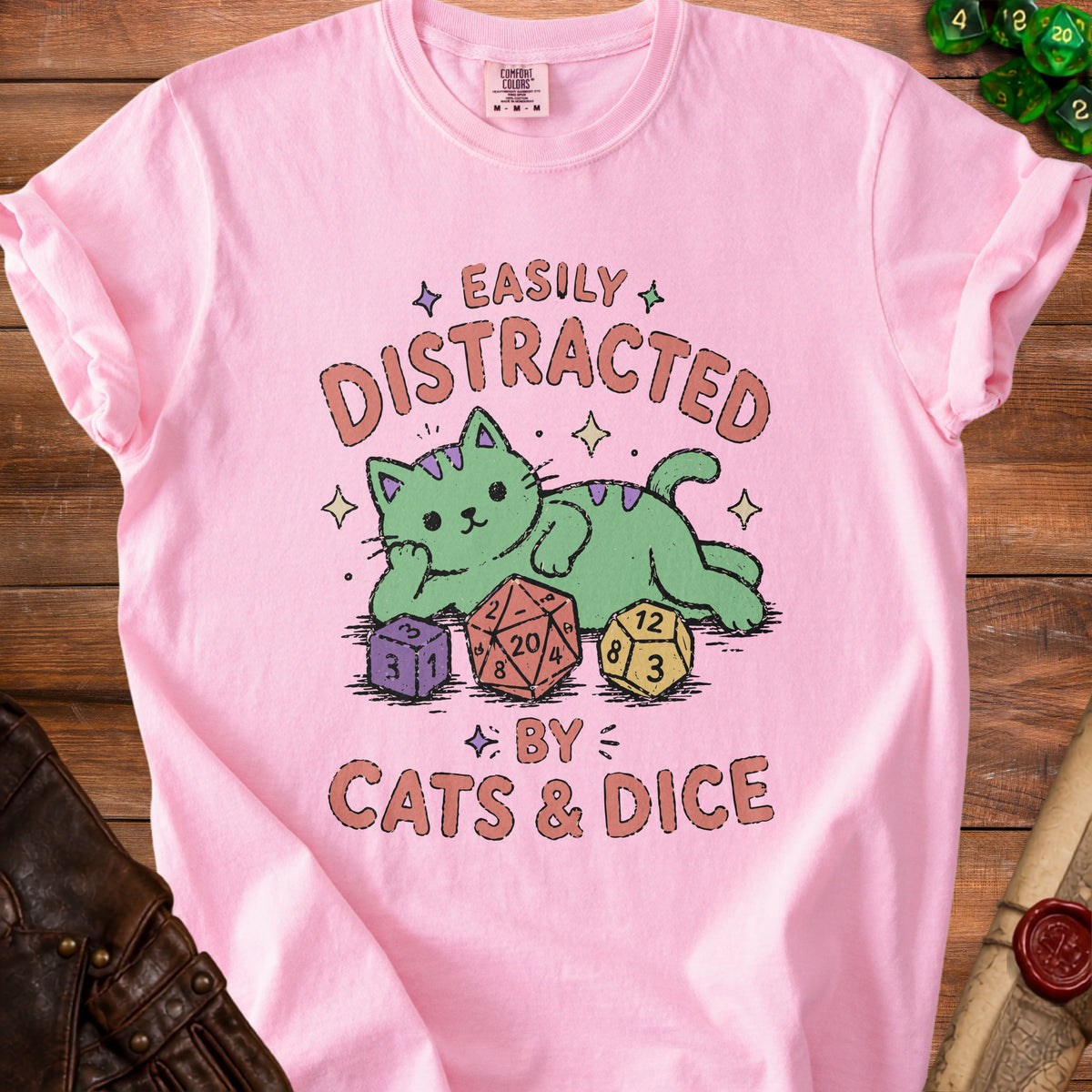 Pink t-shirt with green cat and text "Easily Distracted by Cats & Dice" and dice.