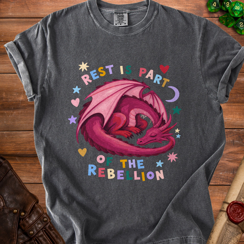 Dark grey t-shirt with a pink sleeping dragon and text "REST IS PART OF THE REBELLION".