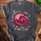 Dark grey t-shirt with a pink sleeping dragon and text "REST IS PART OF THE REBELLION".