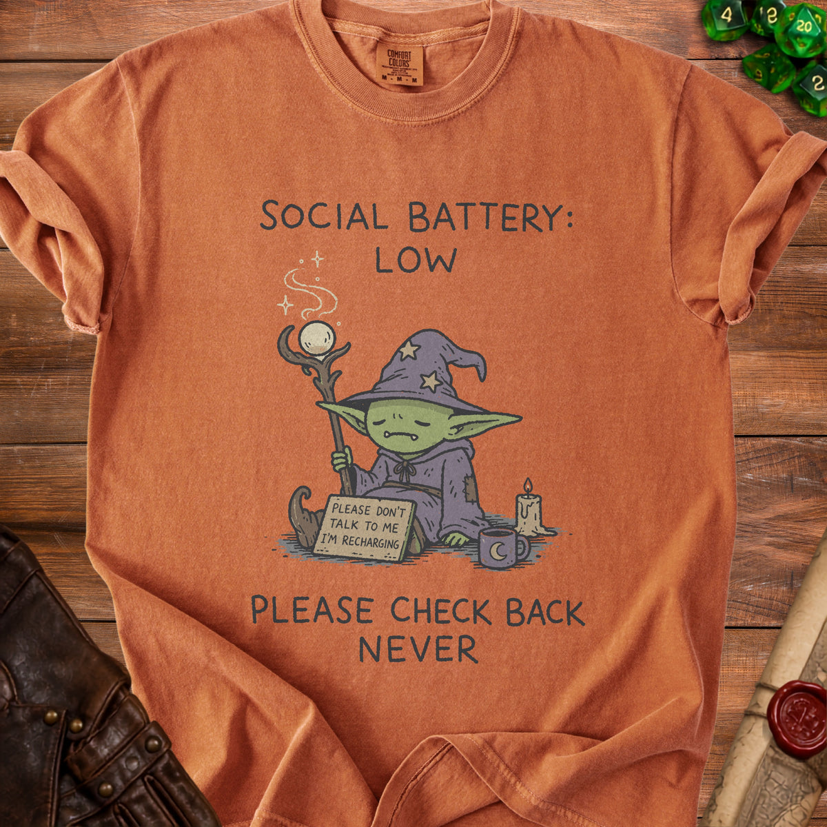 T-shirt with text "Social Battery: Low" and a wizard goblin recharging.