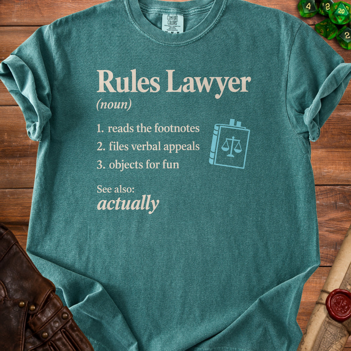 Teal t-shirt with "Rules Lawyer (noun)" definition and law book graphic.