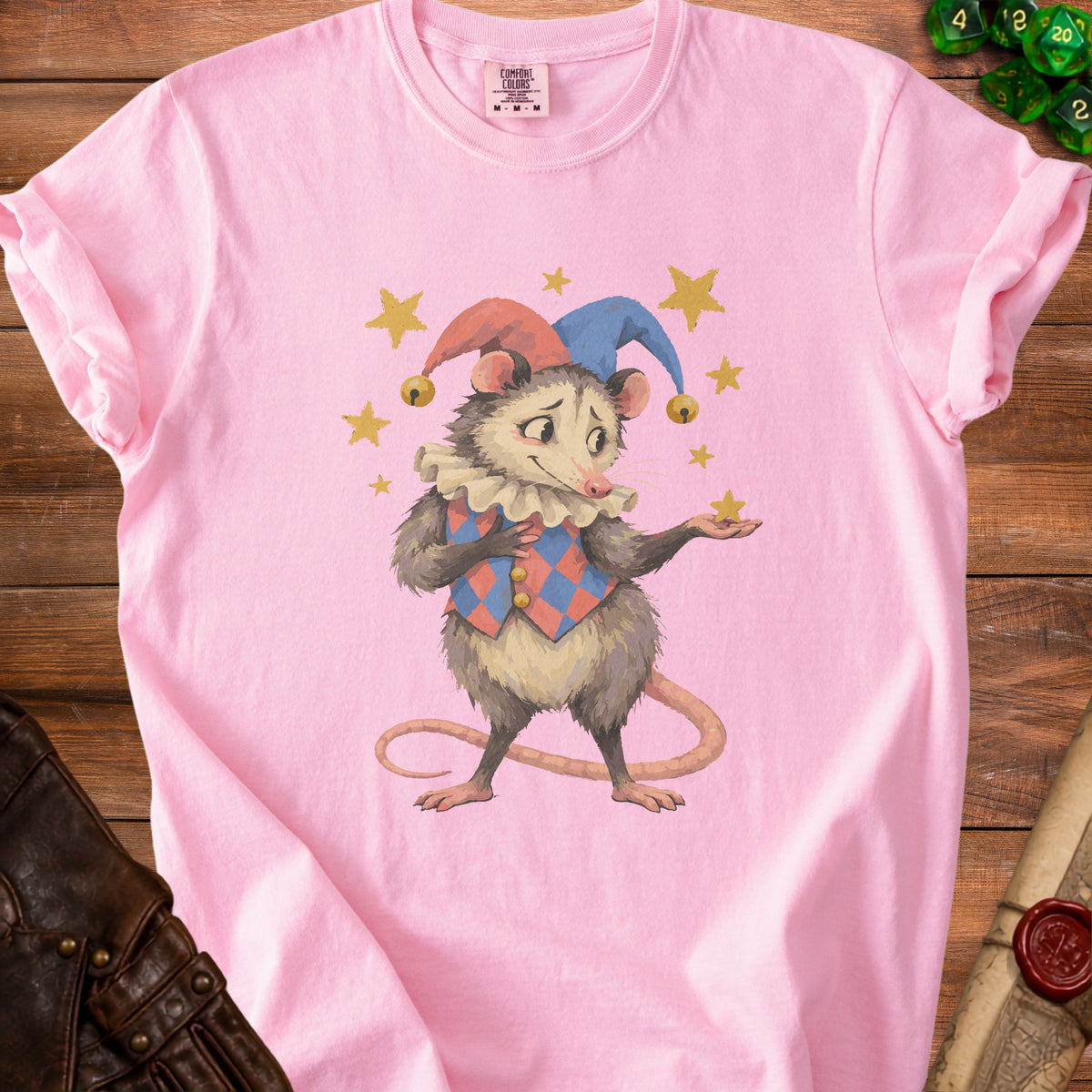 Pink t-shirt with a opossum wearing a jester hat and collar, surrounded by stars.