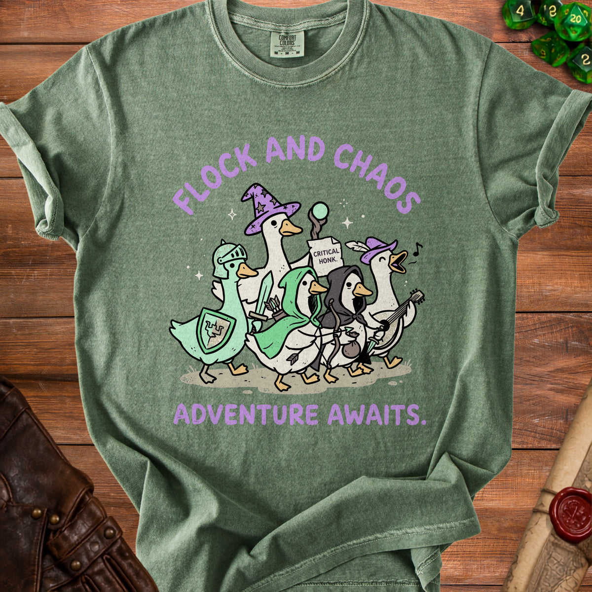 Green t-shirt with cartoon geese in fantasy armor and "Flock and Chaos Adventure Awaits."