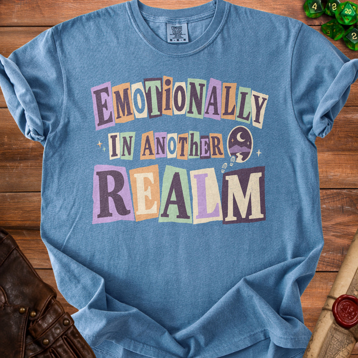 Blue t-shirt with "Emotionally In Another Realm" text and cosmic graphics.