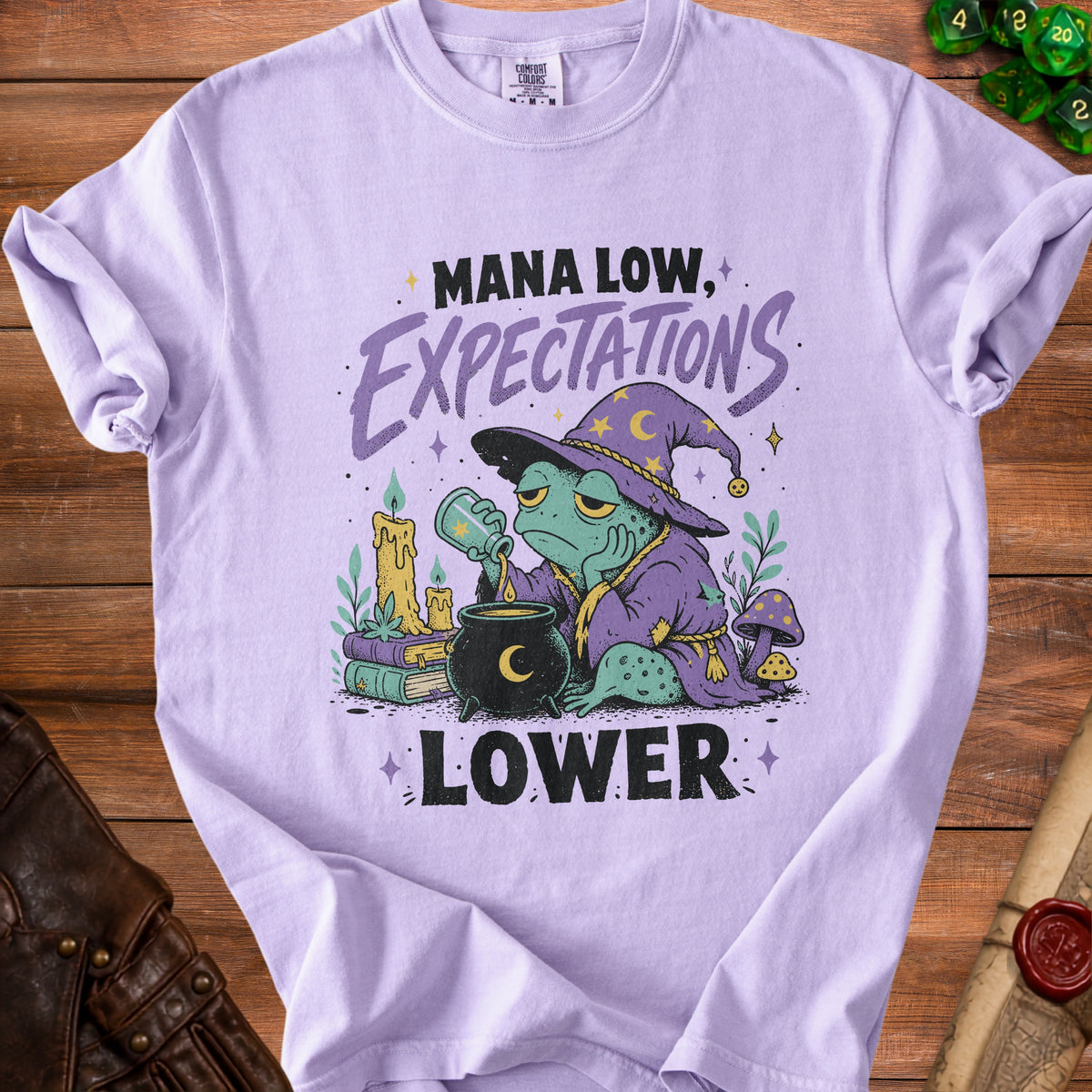 Lavender t-shirt with frog wizard graphic saying "Mana low, expectations lower."
