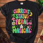 Black t-shirt with "Current Status Feral & Magical" in colorful, bubbly text.