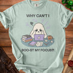 Light blue t-shirt graphic with a ghost on a laptop, books, and text "Why Can't I Boo-st My Focus?!".