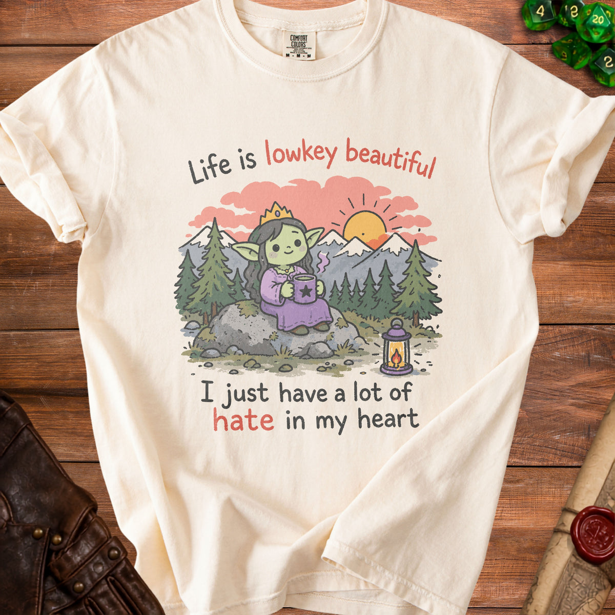 Cream t-shirt with cartoon goblin on rock, sunset, and text "Life is lowkey beautiful I just have a lot of hate in my heart".