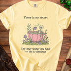 Yellow t-shirt with skeleton in teacup graphic and text: "There is no secret. The only thing you have to do is continue."