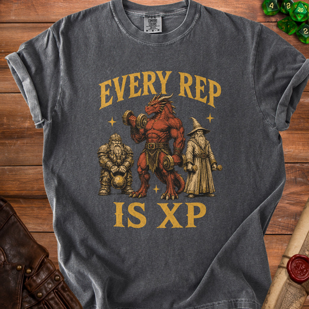 Dark gray t-shirt with a Comfort Colors tag featuring a dragon, dwarf, and wizard lifting weights with text "EVERY REP IS XP".