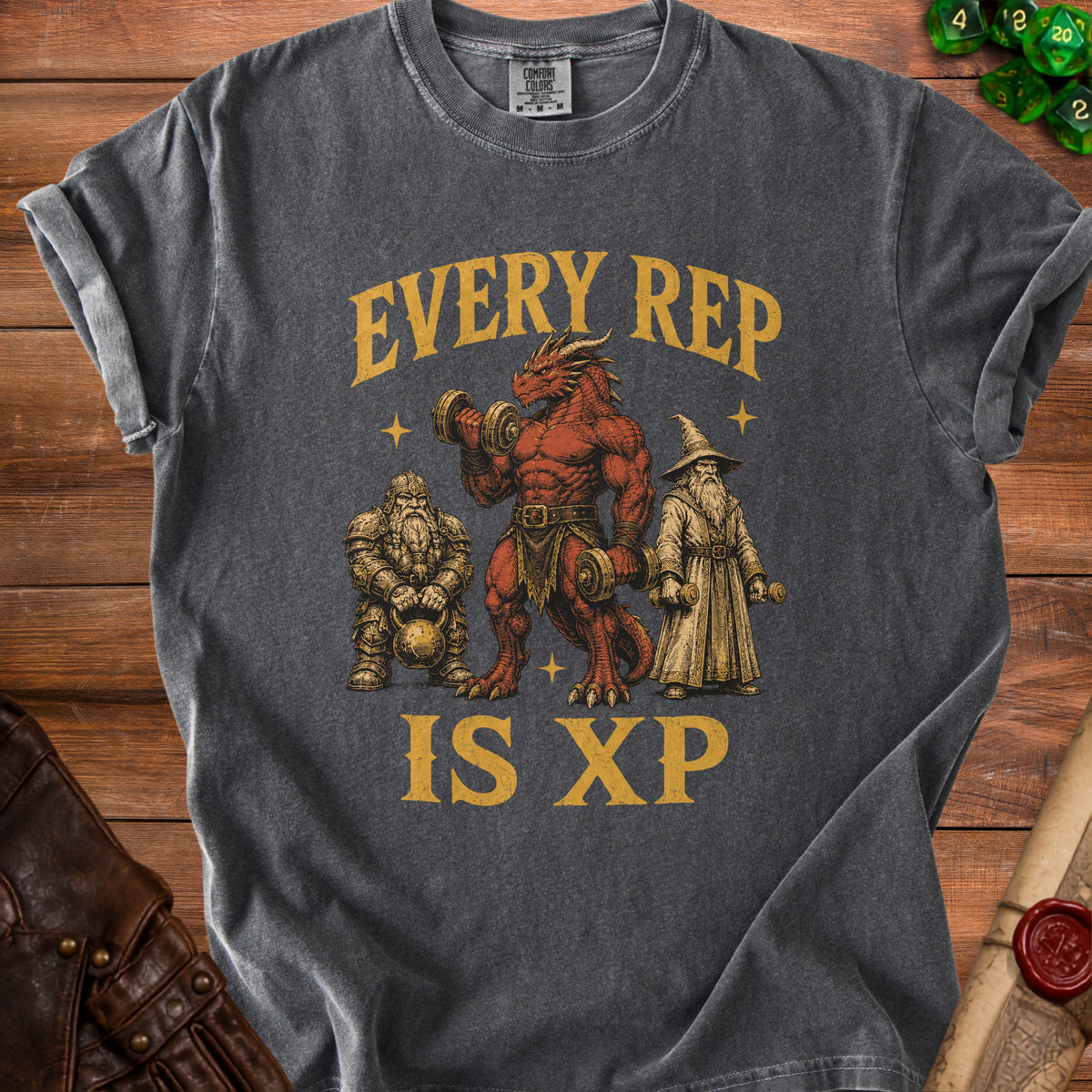 Dark gray t-shirt with a Comfort Colors tag featuring a dragon, dwarf, and wizard lifting weights with text "EVERY REP IS XP".
