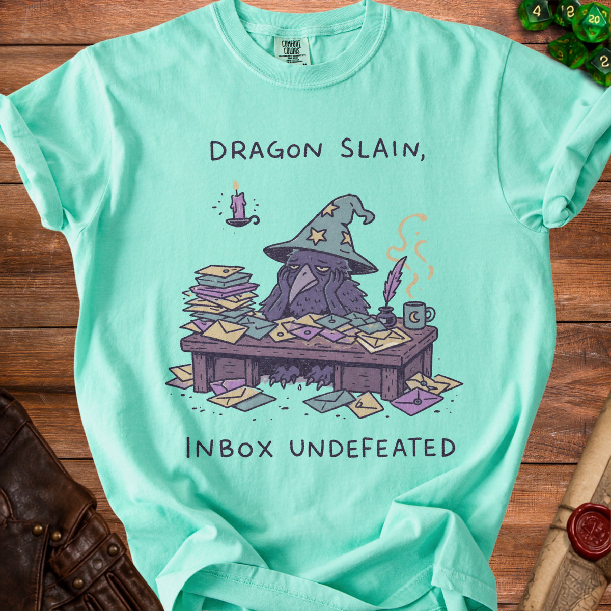 Aqua t-shirt with a crow wizard overwhelmed by mail, reading "DRAGON SLAIN, INBOX UNDEFEATED".