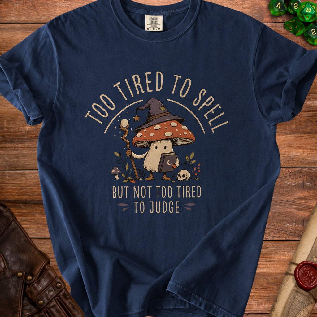 Navy t-shirt with a mushroom wizard graphic reading "Too tired to spell but not too tired to judge."