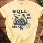 Yellow t-shirt with dark blue print of a possum holding dice and text "Roll Like You Mean It".