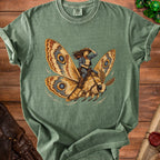 Green t-shirt featuring a woman in cowboy attire riding a moth.