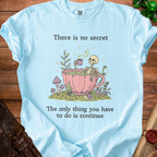 Light blue t-shirt with skeleton in teacup graphic and text: "There is no secret. The only thing you have to do is continue."