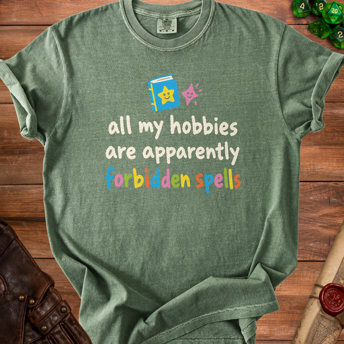 Green t-shirt with text "all my hobbies are apparently forbidden spells".