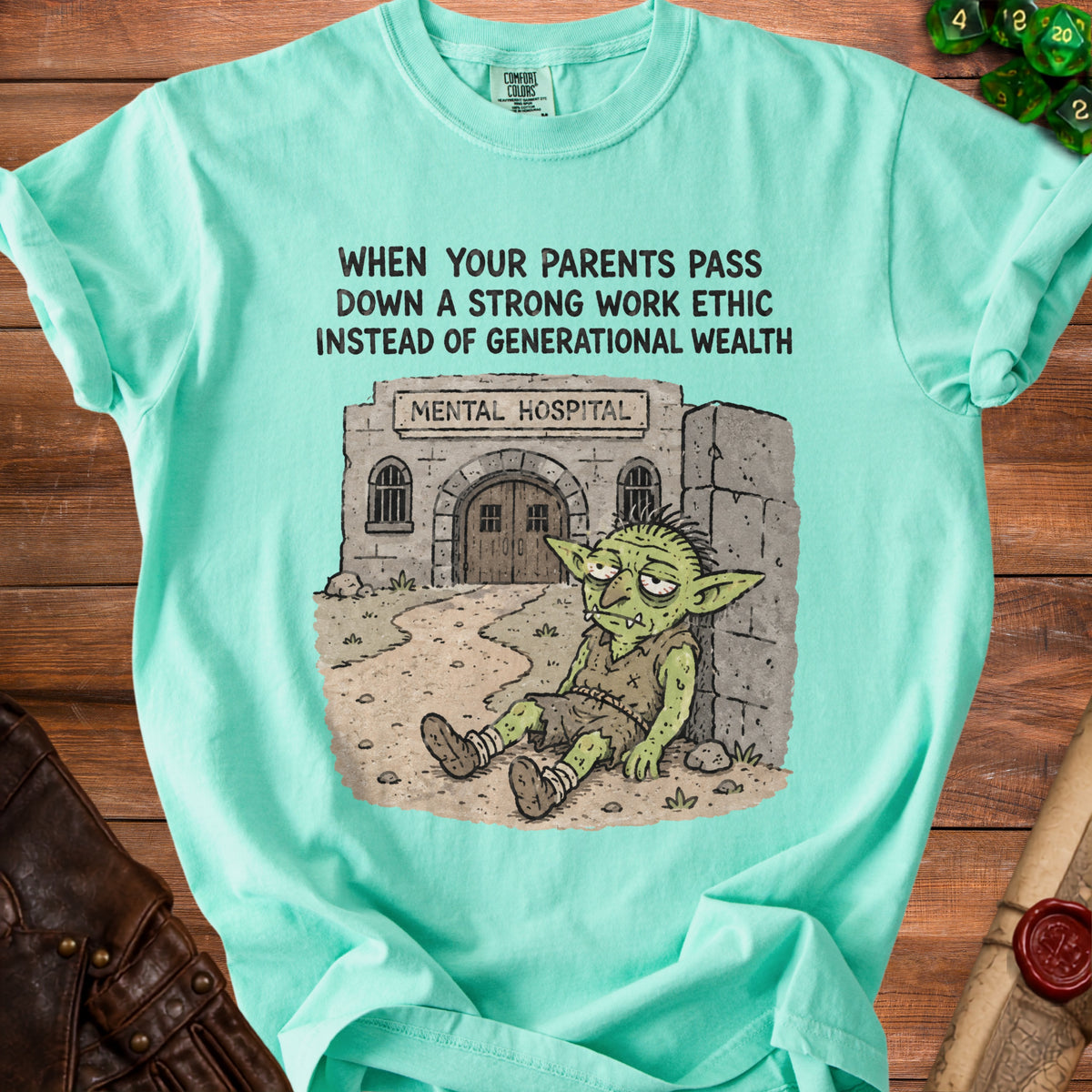 Mint green t-shirt with cartoon of tired goblin outside "Mental Hospital" and text "When your parents pass down a strong work ethic instead of generational wealth."