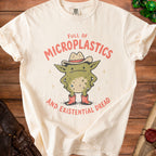 Cream t-shirt with a cartoon monster wearing a cowboy hat and boots, stating "Full of Microplastics and Existential Dread".