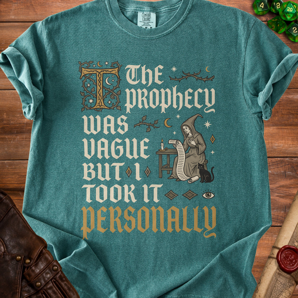 Teal t-shirt with "The prophecy was vague but I took it personally" text and a witch illustration.