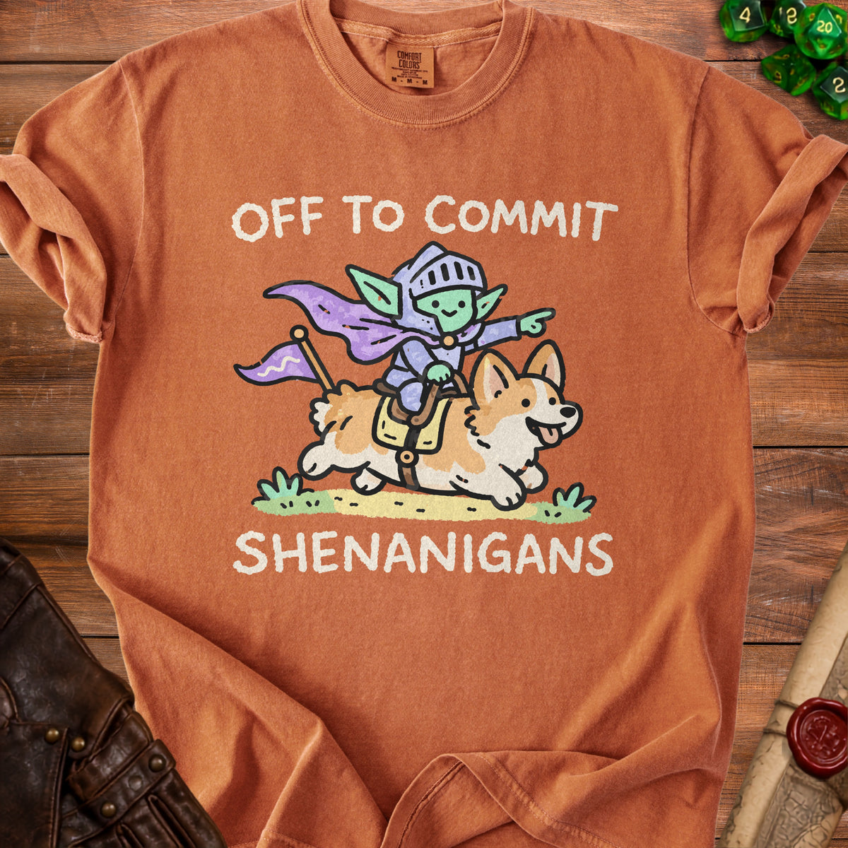 Orange t-shirt with cartoon goblin knight riding a corgi, reading "OFF TO COMMIT SHENANIGANS".