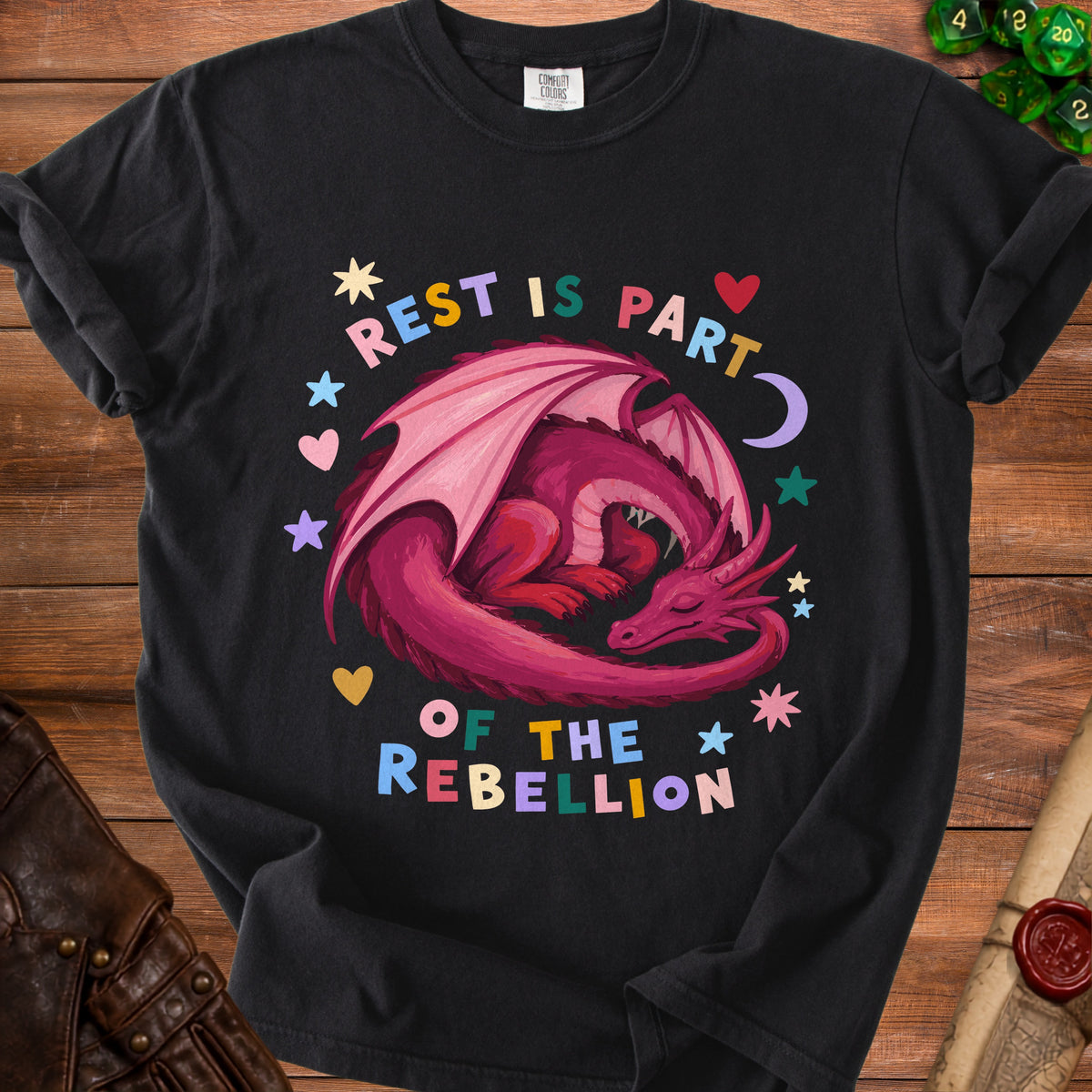 Black t-shirt with a sleeping pink dragon and text "REST IS PART OF THE REBELLION".