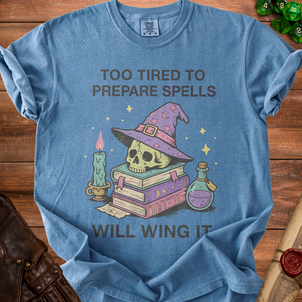 Blue t-shirt with witchy skull, books, candle, and potion illustration.