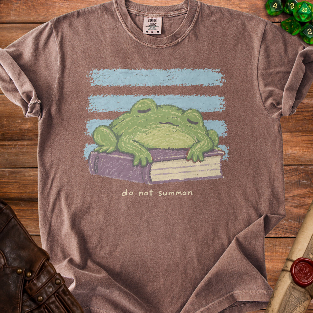 Brown t-shirt with a green frog sleeping on a book, "do not summon" text.