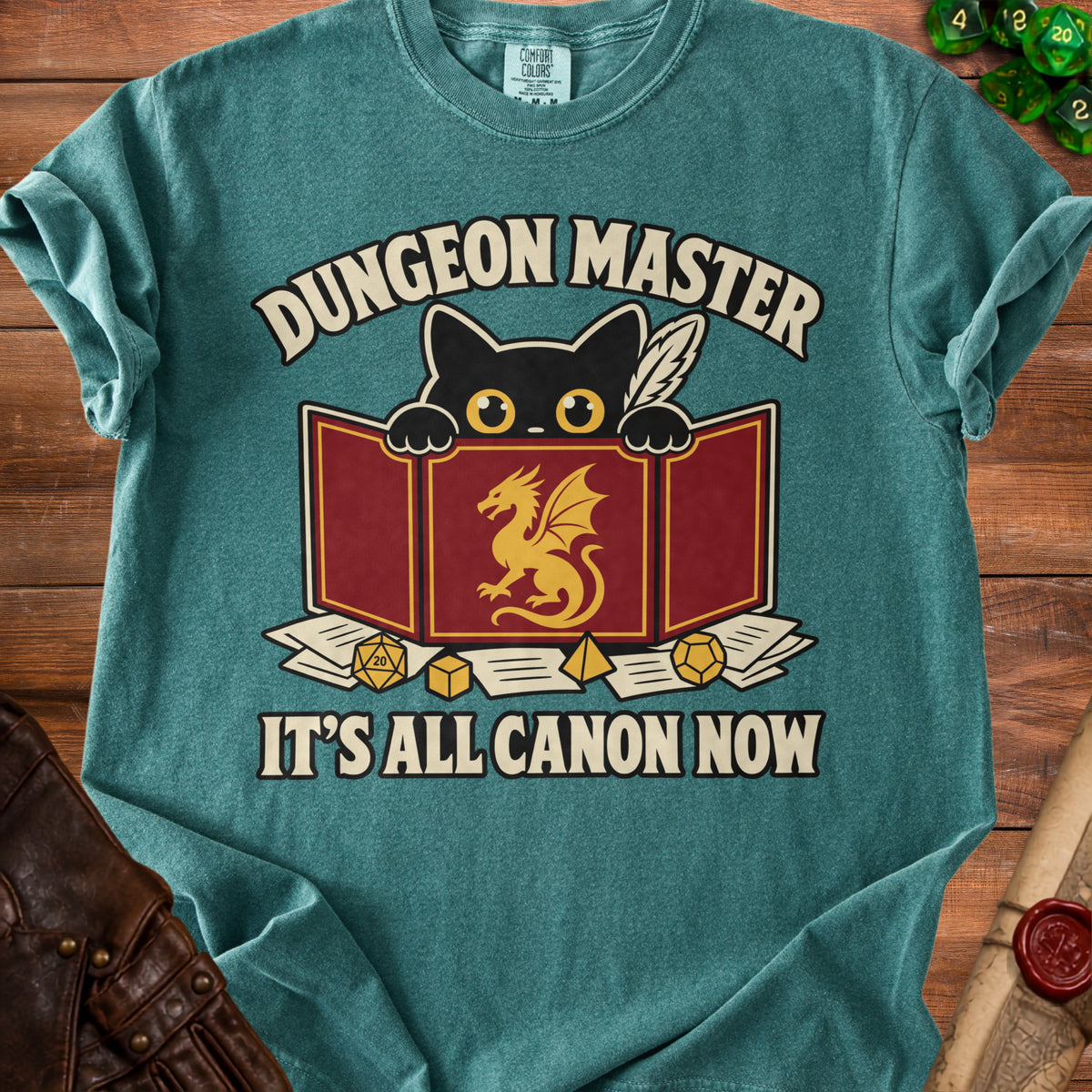 Teal t-shirt with black cat and gold dragon graphic reading "Dungeon Master, It's All Canon Now."
