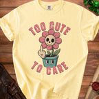 Yellow t-shirt with "Too Cute To Care" text and a cartoon skull flower.