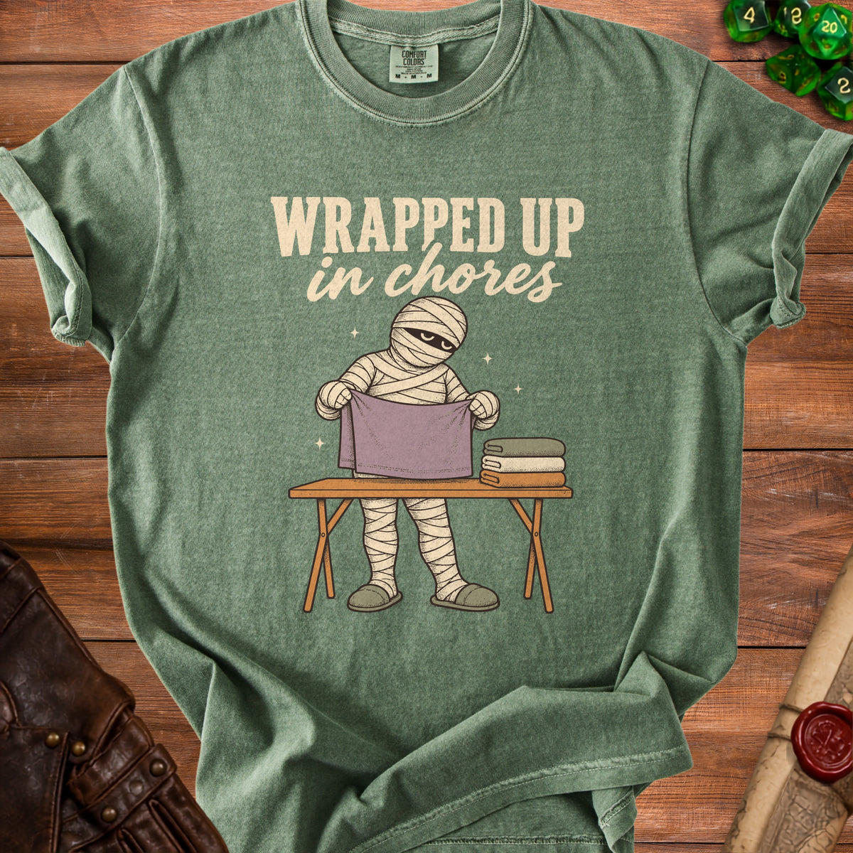 Green t-shirt with mummy character and text "Wrapped Up in Chores".