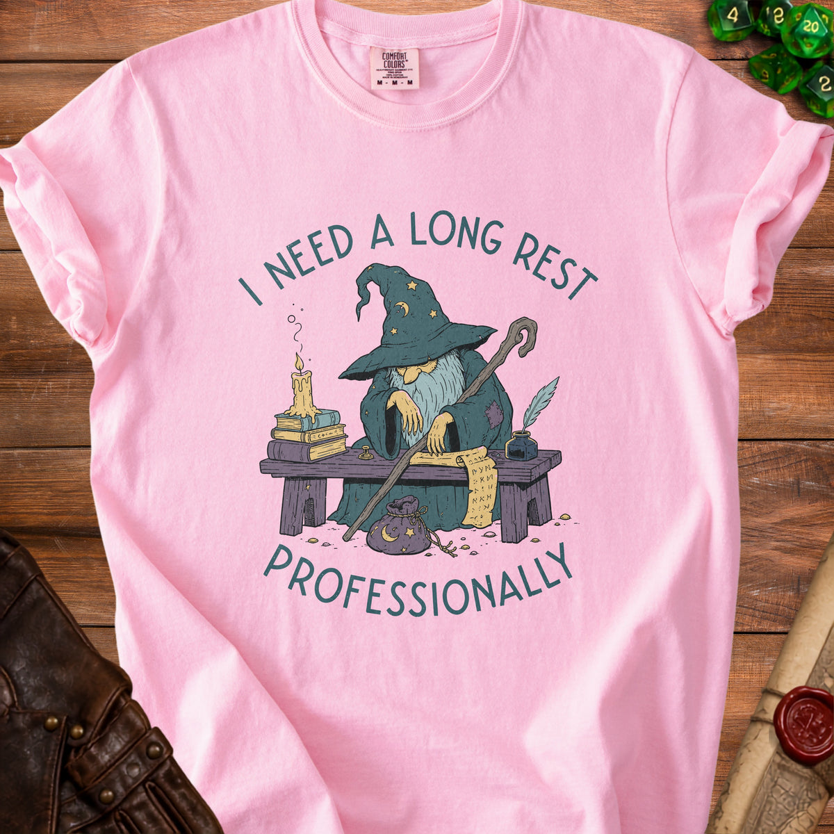 Pink t-shirt with graphic of wizard saying "I need a long rest professionally."