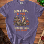 Purple t-shirt with cartoon cats and dog knights fighting, text "Not a phone in sight. Just people living in the moment."