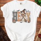 White t-shirt with "HEY" text featuring a ghost with witch hat and brooms.