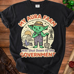 Black t-shirt with "My Aura Farm was Shut Down by the Government" text and a sad goblin farmer graphic.