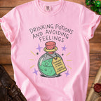 Pink t-shirt with "Drinking Potions and Avoiding Feelings" and a potion with a tag.