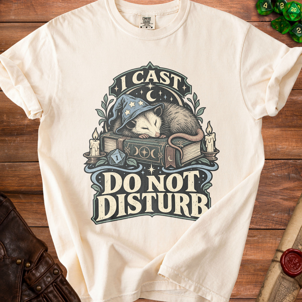 Off-white t-shirt featuring a sleeping opossum in a wizard hat on a book with the text I Cast Do Not Disturb.