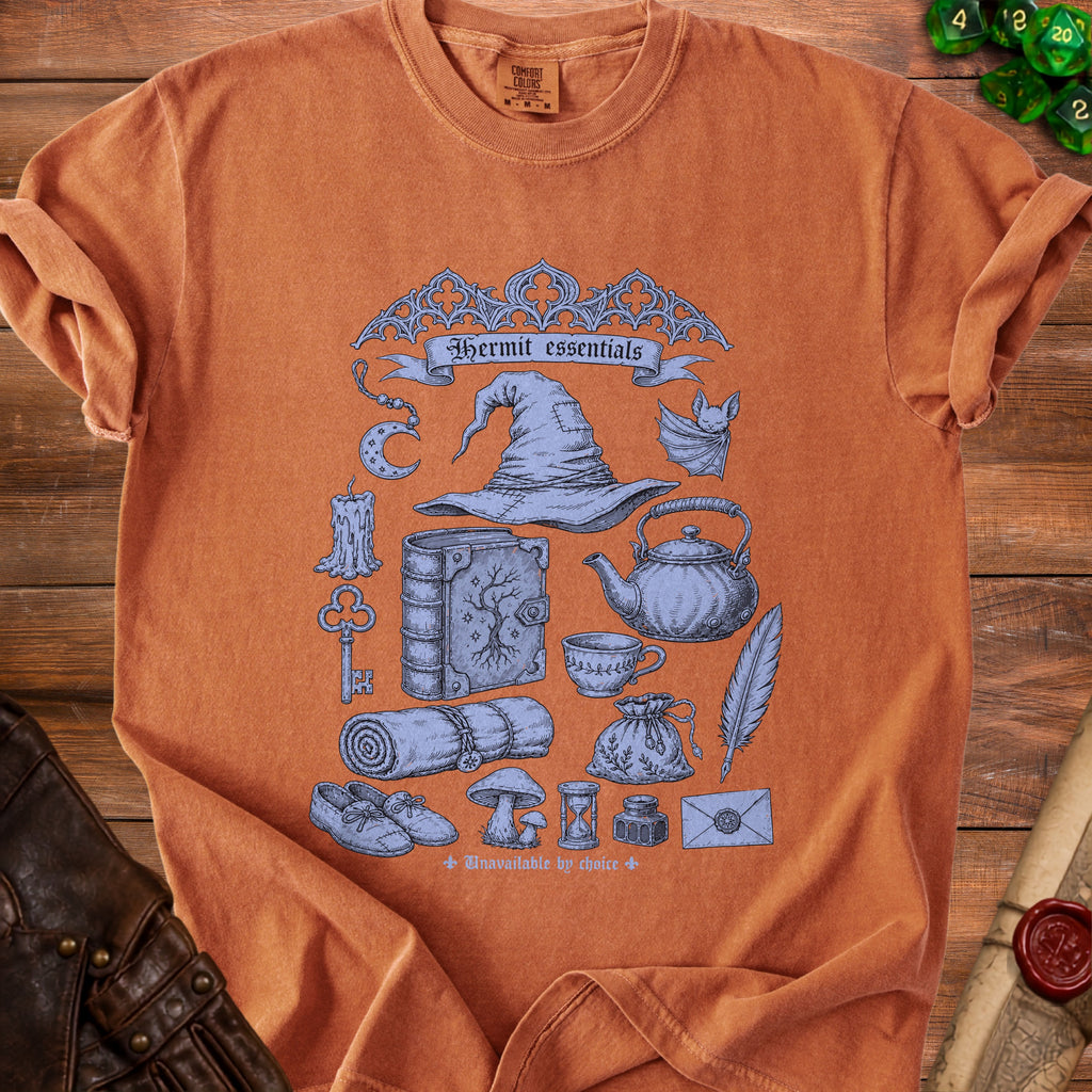 Orange t-shirt with blue Hermit essentials graphic including hat, book, and spell components.