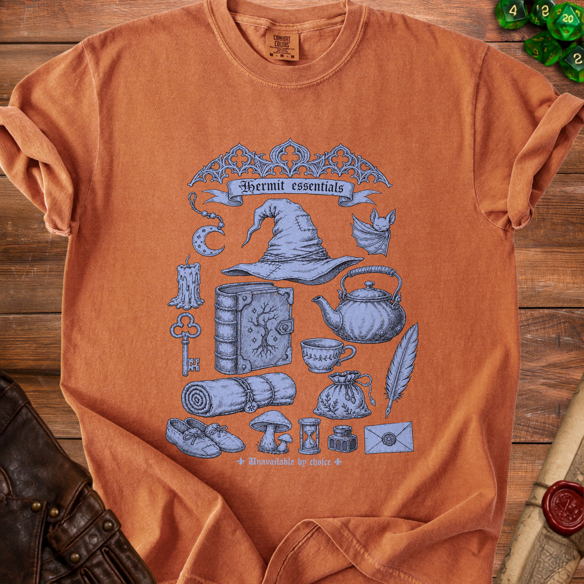 Orange t-shirt with blue Hermit essentials graphic including hat, book, and spell components.