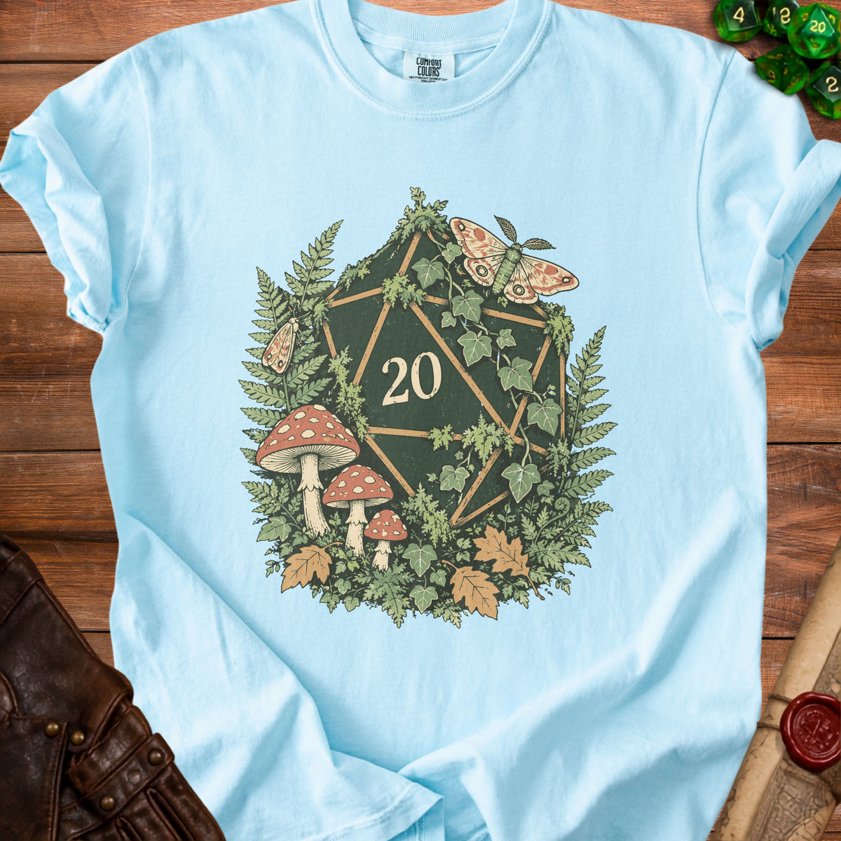 Light blue t-shirt with a forest-themed d20 die, moths, mushrooms, and ferns design.