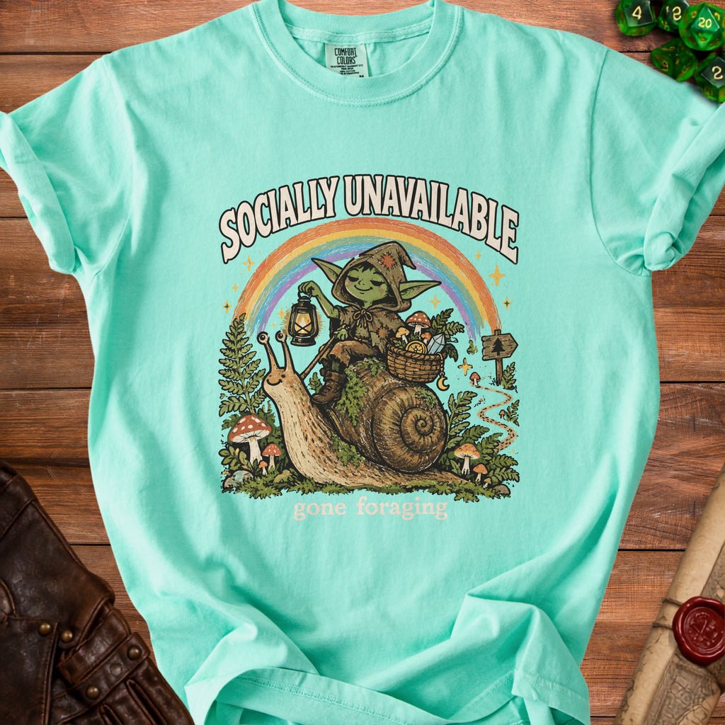 Mint t-shirt with graphic of goblin riding snail under rainbow, "Socially Unavailable" and "gone foraging" text.