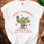 White t-shirt with a cartoon goblin holding a club and skull, reading "Reject Modernity Embrace Being a Silly Little Goblin".
