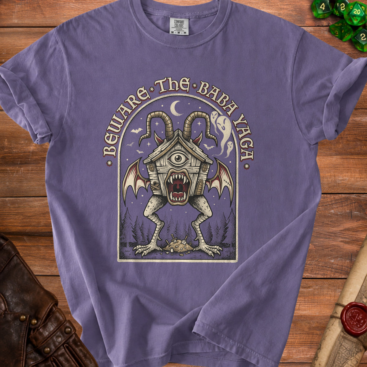 Purple t-shirt featuring a creature with a house for a head and the text "Beware The Baba Yaga".