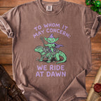 Brown t-shirt with a goblin riding a dinosaur and text "WE RIDE AT DAWN".